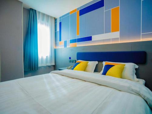 a bedroom with a large white bed with colorful pillows at 7 Days Inn Xi'an Railway Station in Xi'an