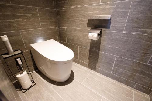 a bathroom with a toilet in a tiled wall at 山人 Oga in Oga