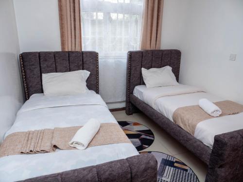 two twin beds in a room with a window at Perfect Palm Condos-P2 in Nakuru