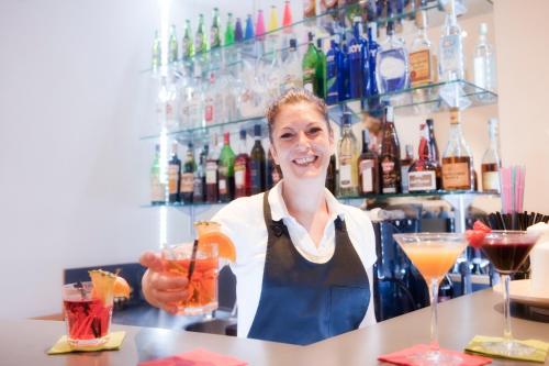 a woman behind a bar holding a drink at Best Western Ars Hotel in Rome