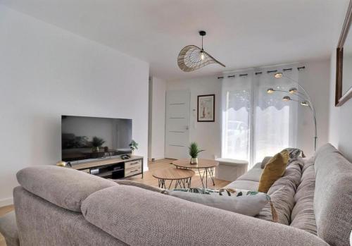 a living room with a couch and a tv at Ker Phan Cozy urban cottage with hot tub in Saint-Aubin-du-Cormier
