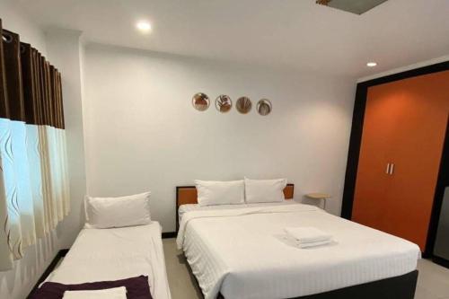 a bedroom with two beds with white sheets at JT Place Buriram in Buriram