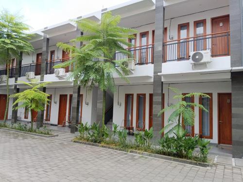 a row of buildings with palm trees in front of them at Rauda Living Space Syariah in Pasuruan