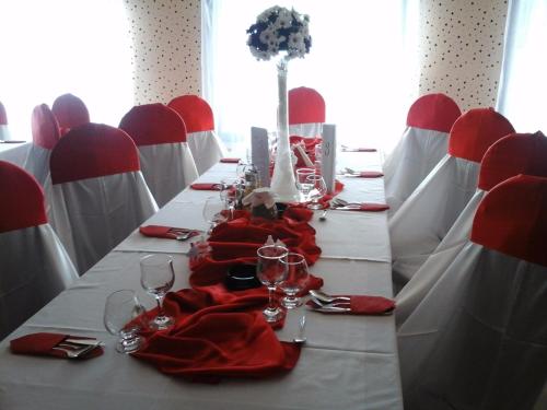 ペトロシャニにあるPensiune Restaurant Casa Sofiaの長テーブル(赤いナプキンとワイングラス付)