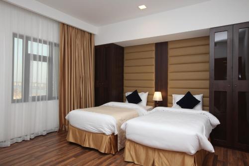 a hotel room with two beds and a window at Golden Tulip Al Khobar Suites in Al Khobar