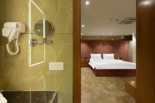 ヴァドーダラーにあるSunday Hotel Vadodaraのベッドルーム1室(ベッド1台、鏡付きシャワー付)