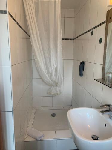 a white bathroom with a sink and a shower at Hotel Bistrot FINE in Anglet