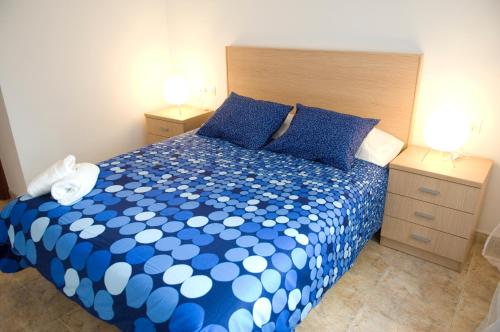 a bedroom with a blue and white bed with two night stands at Apartments Figueres in Figueres