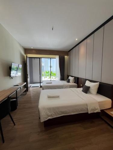 a hotel room with two beds and a desk at M-LIVIN Hotel in Pangkal Pinang