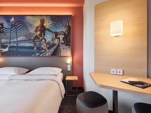 a hotel room with a bed and a desk and a painting at B&B HOTEL Emmerich in Emmerich