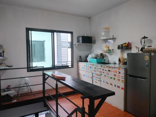 a kitchen with a table and a refrigerator at Den Nest Hostel KRABI in Ban Nong Chaeng