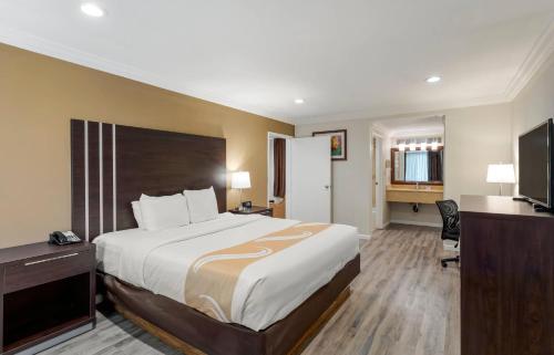 a hotel room with a large bed and a desk at Quality Inn Long Beach - Signal Hill in Long Beach
