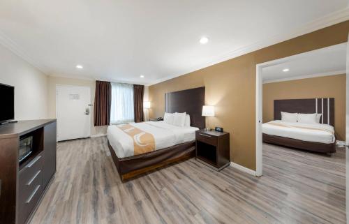 a hotel room with two beds and a flat screen tv at Quality Inn Long Beach - Signal Hill in Long Beach