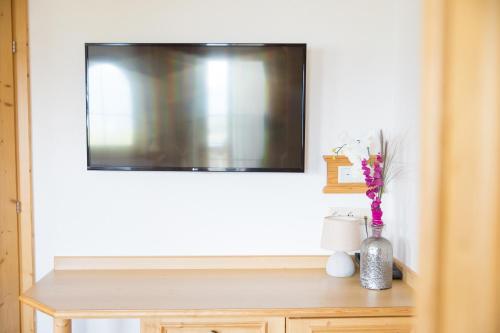 a television on a wall above a table with a vase of flowers at Alpenkönig in Zell am Ziller