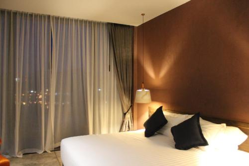 a bedroom with a white bed and a window at The Glory River Kwai Hotel in Kanchanaburi