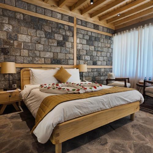 a bedroom with a large bed and a brick wall at Dera Lamsa Resort Shigar in Shigar