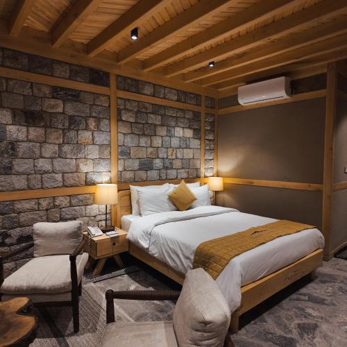a bedroom with a large bed and a chair at Dera Lamsa Resort Shigar in Shigar
