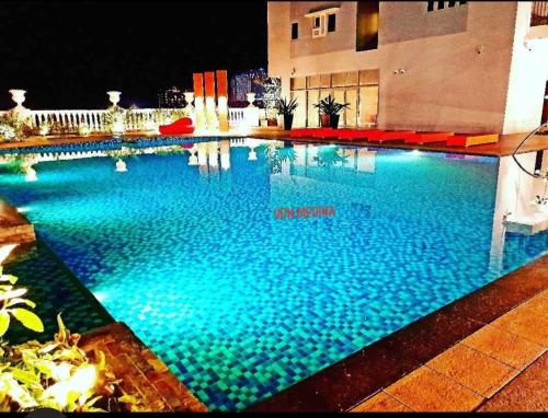 a large swimming pool with blue water at night at Lafayette Park Square with balcony facing pool view in Cari Mayor