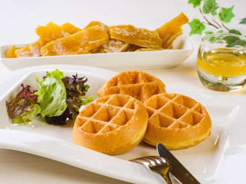 a white plate with waffles and a bowl of greens at Comfort Inn Tsuchiura Ami in Tsuchiura