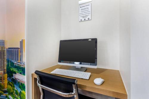 a desk with a computer monitor and a keyboard and mouse at Clarion Pointe Morrow - Atlanta South in Morrow