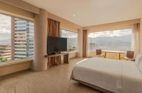 a hotel room with a bed and a flat screen tv at V Grand Hotel, a member of Radisson Individuals in Medellín