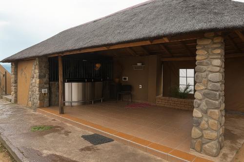 a building with a thatched roof with a patio at Fuleng Guest House - Quthing in Quthing