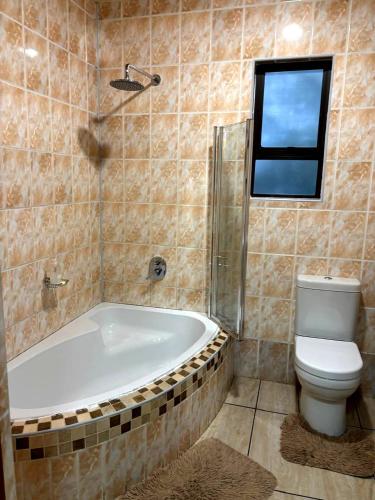 a bathroom with a tub and a toilet and a window at Fuleng Guest House - Quthing in Quthing