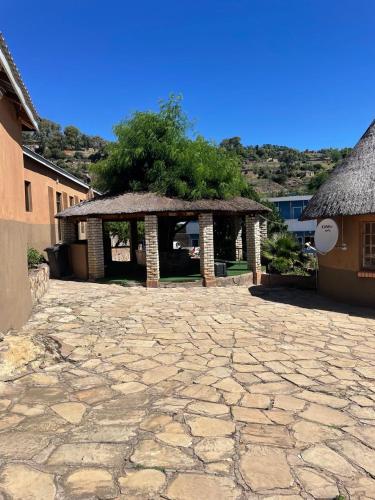 a stone courtyard with a pavilion with a tree at Fuleng Guest House - Quthing in Quthing