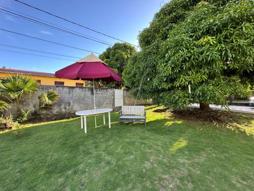 a table with an umbrella and a chair in a yard at Appt F2 BELLISSIMA in Baie-Mahault