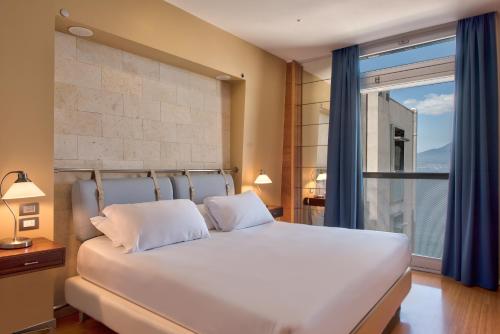 a bedroom with a white bed and a large window at Towers Hotel Stabiae Sorrento Coast in Castellammare di Stabia