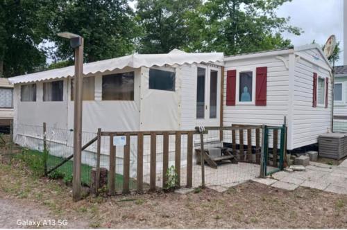 a small white house with a fence in a yard at Mobile Home 40m2 6 personnes in Saint-Étienne-de-Chigny