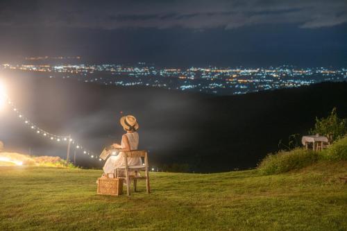 a woman sitting on a chair on a hill at night at Phupetra ภูเปตรา in Ban Thung Phan Ha