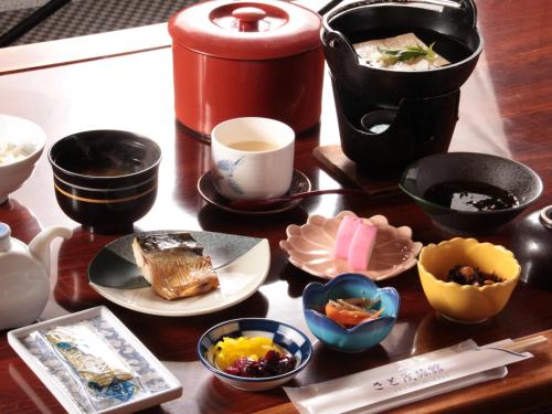 a table with bowls and cups of food on it at Satomo Ryokan in Kyoto