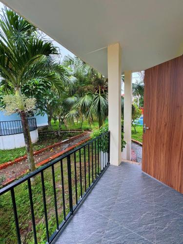 a balcony with a wooden door and palm trees at Villa Sea in Trà Cổ