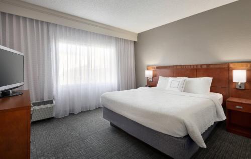 a hotel room with a bed and a flat screen tv at Courtyard by Marriott Fort Myers Cape Coral in Fort Myers