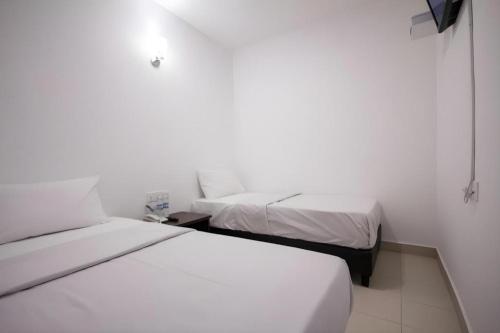 two beds in a small room with white walls at D Nice Hotel in George Town