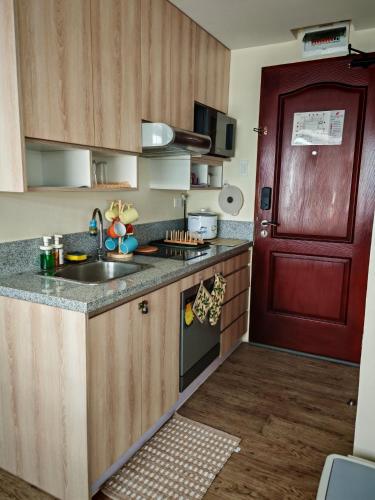 a small kitchen with a sink and a red door at Family-Friendly 2BR Staycation near Nuvali & Enchanted Kingdom in Puting Kahoy