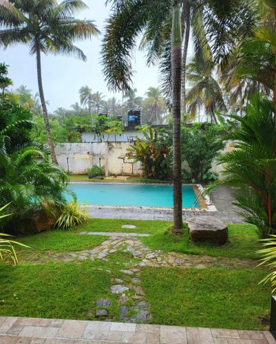a swimming pool with palm trees in a yard at oZean Villa in Talpe