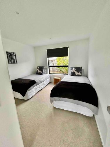 a bedroom with two beds and a window at Karapiro Lakeside in Karapiro