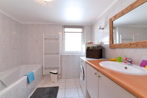 a bathroom with a tub and a sink and a bath tubermottermott at Gite Géranium*** in Eguisheim
