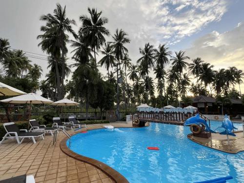 a large blue pool with chairs and palm trees at Ban Krut Resort in Ban Krut