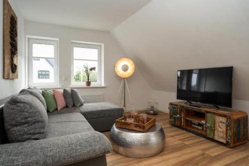 a living room with a couch and a flat screen tv at Sylter Seestern Seepferdchen Loft in Morsum
