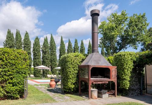 a wood fired oven in a yard with bushes at Tuscany Tower Villa in Capolona