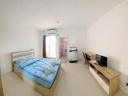 a bedroom with a bed and a television and a desk at Orchid Residence At Amata in Si Racha