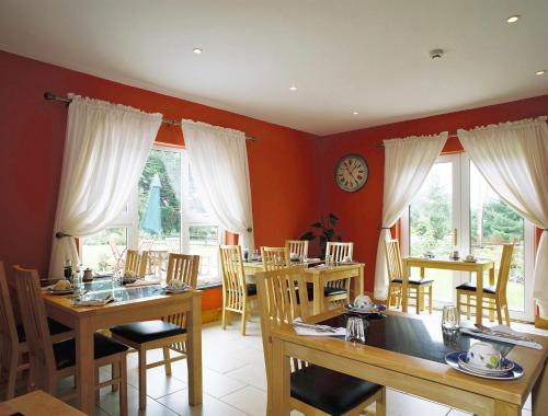 una sala da pranzo con tavoli, sedie e un orologio sul muro di Greenlawn Lodge a Lisdoonvarna