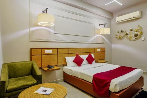 a bedroom with a bed and a chair and a table at Max Hotels Prayagraj in Allahābād