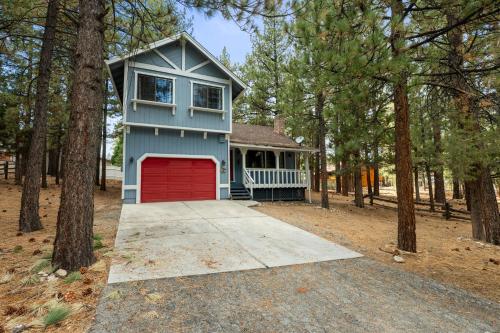 a blue house with a red garage in the woods at Bear Woods 3BR Retreat in Big Bear City