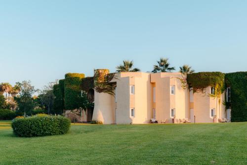 a large building with a grass field in front of it at Mangia's Brucoli, Sicily, Autograph Collection in Brucoli