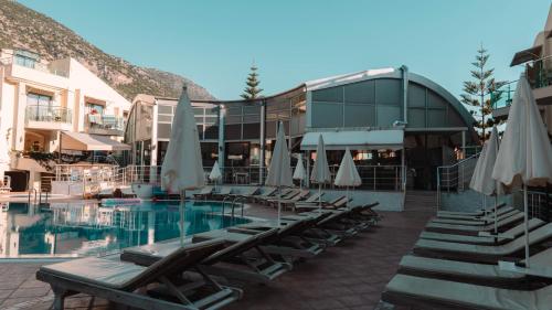 a group of chairs and umbrellas next to a pool at Belcehan Hotel in Oludeniz
