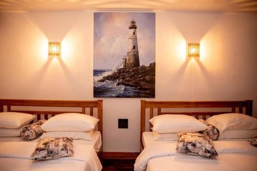 two beds in a room with a painting of a lighthouse at Cara Galle Fort in Galle